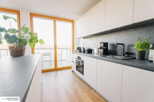 a kitchen with white cabinets and black counter tops at 119 QM - Exklusiv auf 2 Etagen - Werse Loft by youpartments in Münster