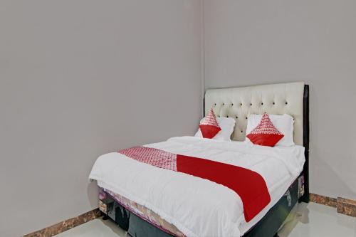 a bedroom with a bed with red and white pillows at Hotel O Putri Homestay Syariah Near SPBU 14.282.694 (Air Hitam) in Pekanbaru