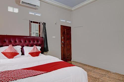 a bedroom with a large bed with red pillows at Hotel O Putri Homestay Syariah Near SPBU 14.282.694 (Air Hitam) in Pekanbaru