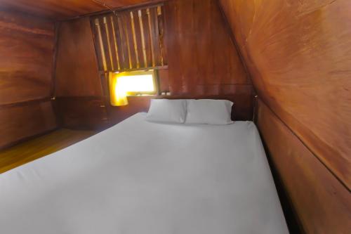 a bed in a small room with a wooden wall at Hotel O Awenk Homestay Near SD Gunung Wakul in Labuan Lombok