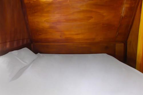 a bed in a small room with a wooden wall at Hotel O Awenk Homestay Near SD Gunung Wakul in Labuan Lombok