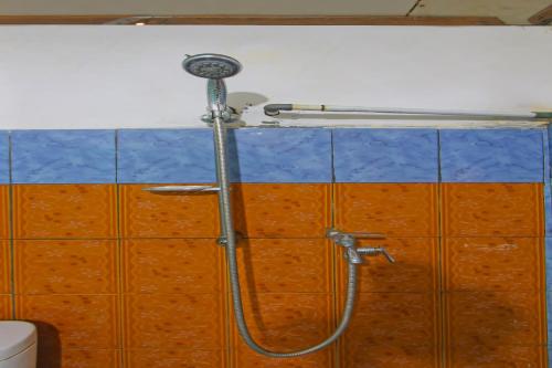 a shower in a bathroom with orange and blue tiles at Hotel O Awenk Homestay Near SD Gunung Wakul in Labuan Lombok