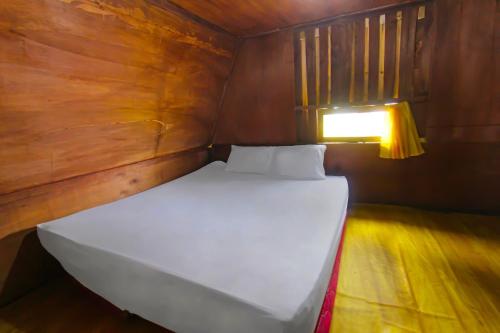 a white bed in a small room with a light at Hotel O Awenk Homestay Near SD Gunung Wakul in Labuan Lombok