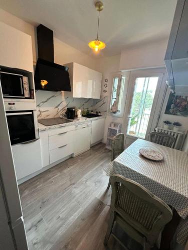 une cuisine avec des placards blancs et une table avec une table dans l'établissement Résidence Fleur De Mai - Joli T3 5 couchages proche du port de Sanary sur Mer MAE-8871, à Sanary-sur-Mer