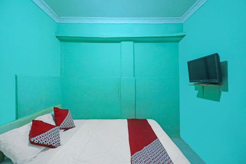 a bedroom with a bed with a tv on the wall at Hotel O Faraas Homestay Syariah in Nongsa