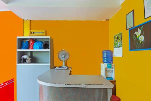a room with an orange wall and a table with a fan at Hotel O Faraas Homestay Syariah in Nongsa