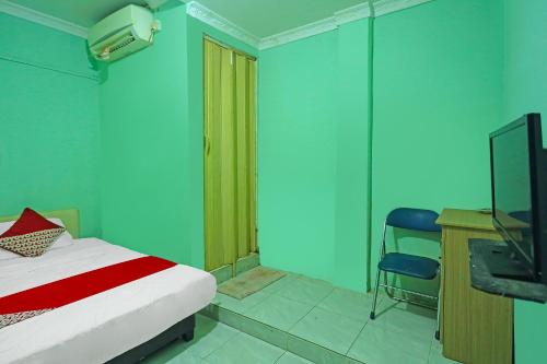 a bedroom with a bed and a desk and a television at Hotel O Faraas Homestay Syariah in Nongsa