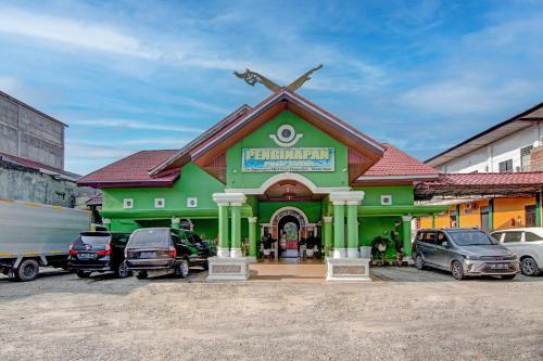 a green building with cars parked in a parking lot at OYO 92497 Penginapan Pasir Indah SyariahNearMonument Park City Sand Pengaraian in Pasirpengarayan