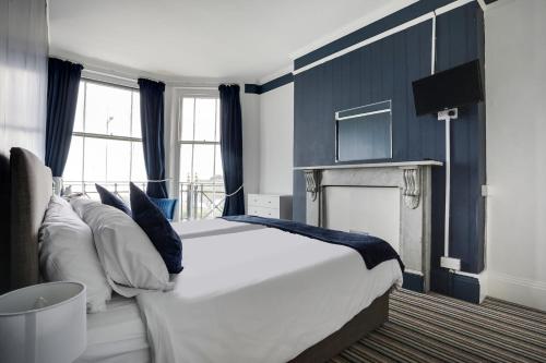 a bedroom with a large white bed and a fireplace at Lord Kitcheners Guest House in Lowestoft