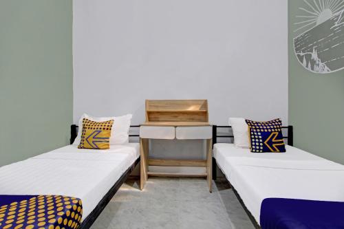 a room with two beds and a desk in it at SPOT ON 92490 Casa Homestay Syariah in Brangsong