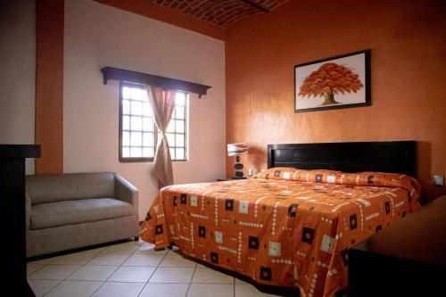 a bedroom with a bed and a chair and a window at Hotel El Dorado - cerca de Chapala y del Aeropuerto in Ixtlahuacán de los Membrillos