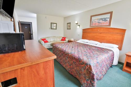 a hotel room with a bed and a flat screen tv at OYO Hotel Pipestone MN, Canterbury Park in Pipestone