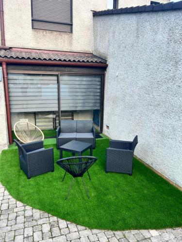 a patio with four chairs and a table on grass at Le Hourmigué maison avec jacuzzi à 15mn de Luchon in Cierp
