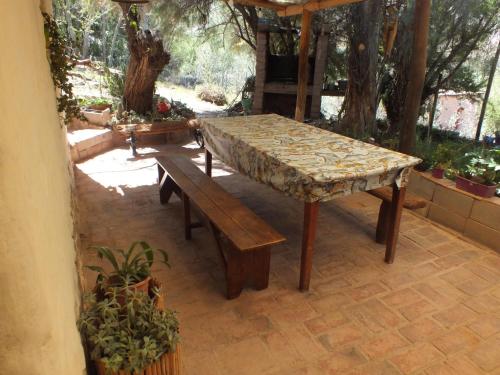 Una mesa y bancos en un patio con árboles. en Casa Minerva, construcción de materiales autoctonos, en Maimará