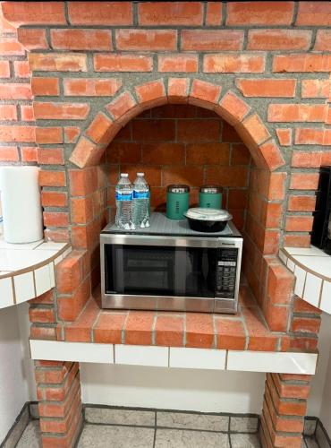 a microwave in a brick oven with water bottles on it at Seaside Adventure Lodging in Ensenada