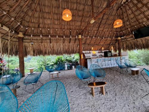 a group of chairs and a bar under a straw roof at Tambo Eco Hotel in La Vega