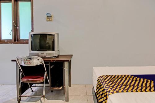 a room with a desk with a tv and a bed at Hotel O Pacar Guesthouse in Pekalongan