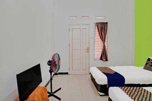 a room with two beds and a tv and a camera at Hotel O Teguh Homestay Syariah in Parit