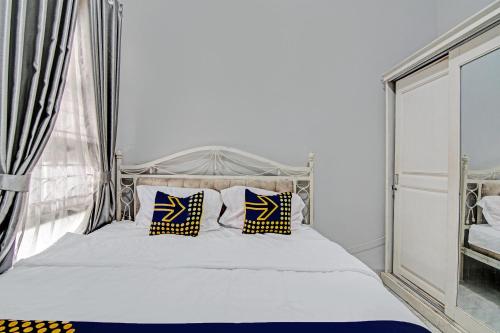 a bedroom with a white bed with blue and yellow pillows at Hotel O Teguh Homestay Syariah in Parit
