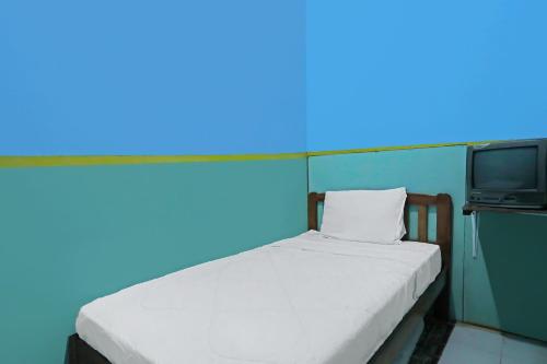 une chambre avec un lit avec un mur bleu et une télé dans l'établissement Hotel O Joyoakis Homestay SyariahNearMall Nagoya Hill, à Nagoya