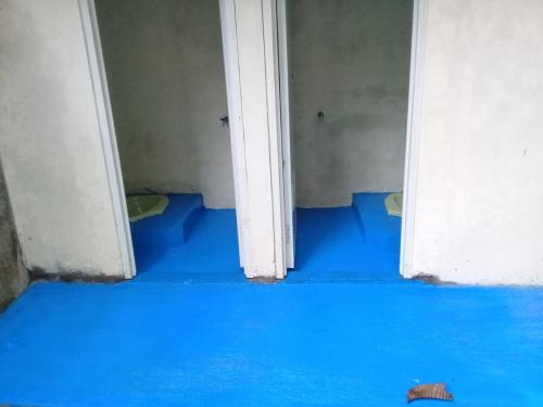 a bathroom with blue floors and a white door at Hotel O Tetirah Homestay in Salatiga