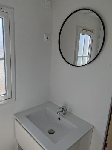 une salle de bain avec un lavabo blanc et un miroir dans l'établissement Mobil Home Le Salicorne, à Noyelles-sur-Mer