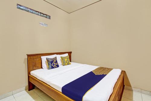 a bed with blue and yellow pillows in a room at Hotel O Timoti Guest House in Potrojayan