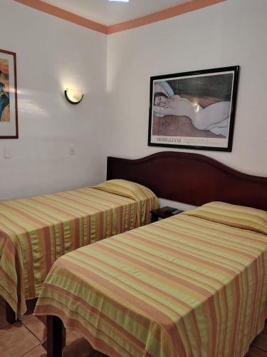 a hotel room with two beds and a picture on the wall at Pousada Pouso do Frade in Pirenópolis
