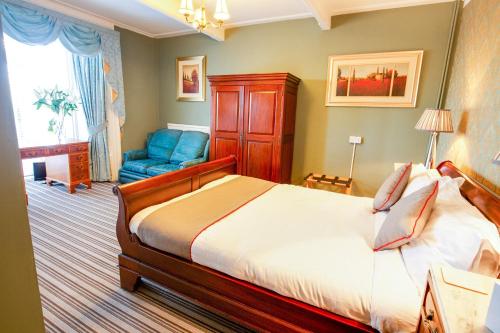 ペンブロークにあるOYO Lamphey Hall Hotelのベッドルーム1室(ベッド1台、青い椅子付)