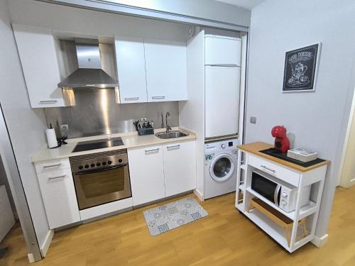 eine Küche mit weißen Schränken und einem Herd mit Backofen in der Unterkunft El Piso de Montse in A Coruña