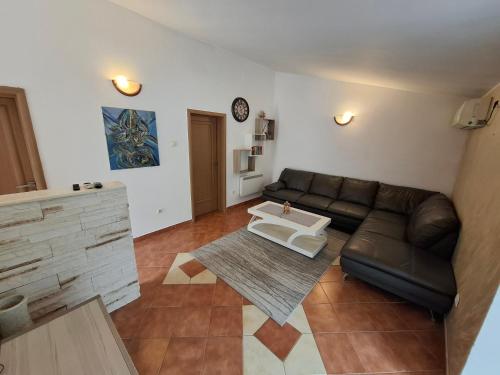 a living room with a leather couch and a table at Nina Apartment in Škaljari