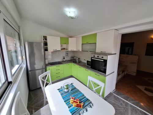a kitchen with green and white cabinets and a table at Nina Apartment in Škaljari
