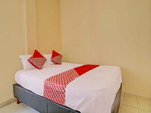 a bed with red and white pillows on it at Hotel O Excellent Kost in Jambi