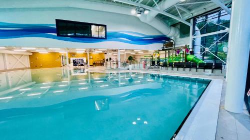 a large swimming pool in a building with a slide at Tor View Lodge with Hot Tub & Sauna - Spa Resort - South Devon in Chudleigh Knighton