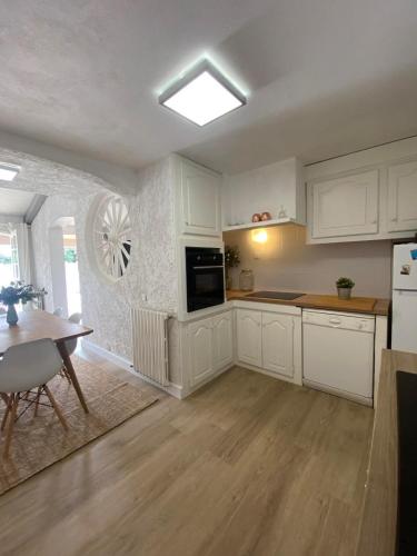 une cuisine avec des armoires blanches, une table et une fenêtre dans l'établissement Villa Saint-Cyprien Corse, à Lecci