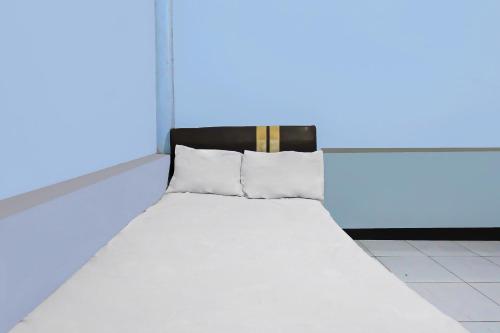 a white bed in a room with a blue light at Hotel O Jati Homestay Near Taman Suranadi in Labuan Lombok
