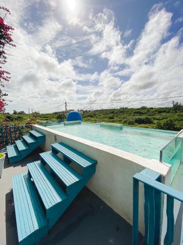 a swimming pool with blue benches in front of it at Pousada La Grécia in Camocim