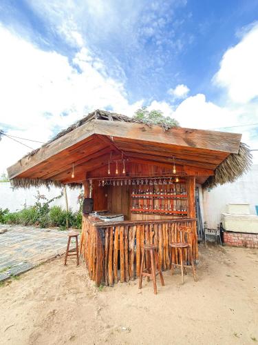 a wooden building with chairs and a bar with a roof at Pousada La Grécia in Camocim