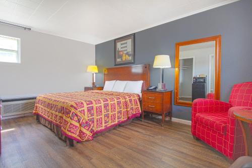 a hotel room with a bed and a red couch at OYO Hotel McAlester OK S Main St in McAlester