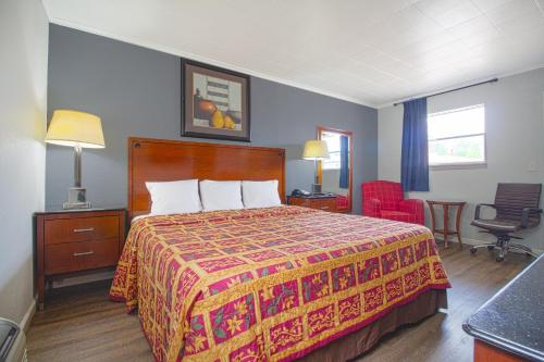 a hotel room with a bed and a chair at OYO Hotel McAlester OK S Main St in McAlester