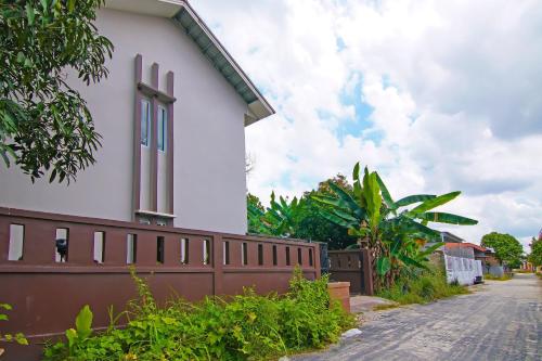 a white building with a fence next to a street at Hotel O Putri Guest House Syariah Near SPBU Rimbo Panjang in Pekanbaru