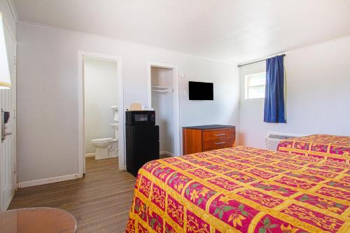 a hotel room with a bed and a bathroom at OYO Hotel McAlester OK S Main St in McAlester