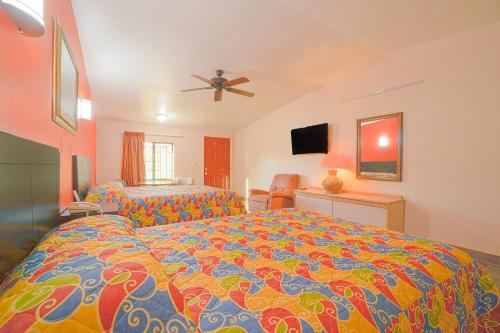 a bedroom with a large bed with a colorful comforter at Vali Ho Motel By OYO Weslaco Mercedes in Weslaco