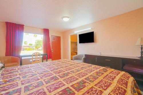 a hotel room with a bed and a flat screen tv at Vali Ho Motel By OYO Weslaco Mercedes in Weslaco