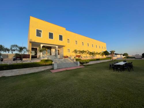 un grand bâtiment jaune avec une table et des chaises dans l'établissement Mannat Resort, à Bikaner