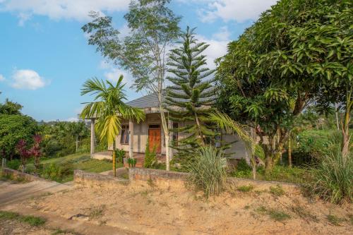 une maison avec des arbres devant elle dans l'établissement Hotel O Homestay Romauli Kampung Radja, à Jambi