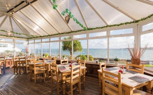 a restaurant with tables and chairs and a view of the ocean at Trecastell Hotel in Amlwch