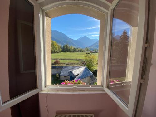 an open window with a view of a house at La Ferme de Gayri, chalet d'exception avec sauna et jacuzzi à 5 minutes de St-Lary Soulan in Vielle-Aure