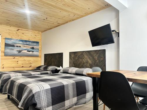 two beds in a room with a table and a tv at Les studios de la mer in Matane