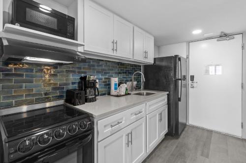 a kitchen with white cabinets and a black refrigerator at Compass Cove in Myrtle Beach